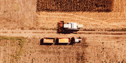 Aerial view of combine harvester pouring corn kernels into cart